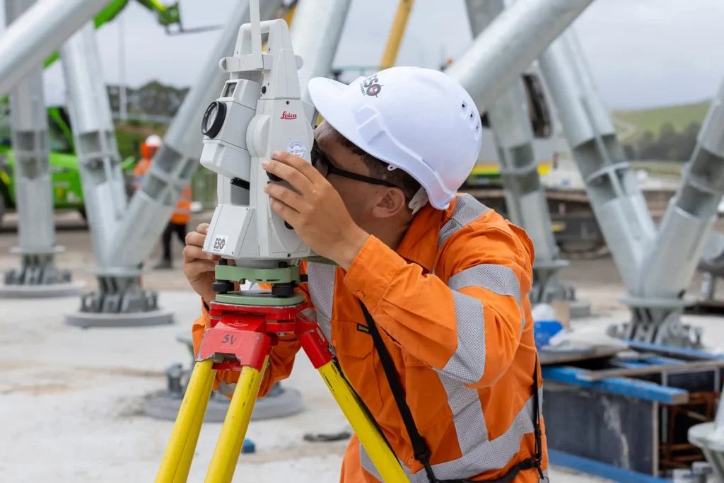 Female surveyor in a hard hat and high visibility clothing on a road construction site